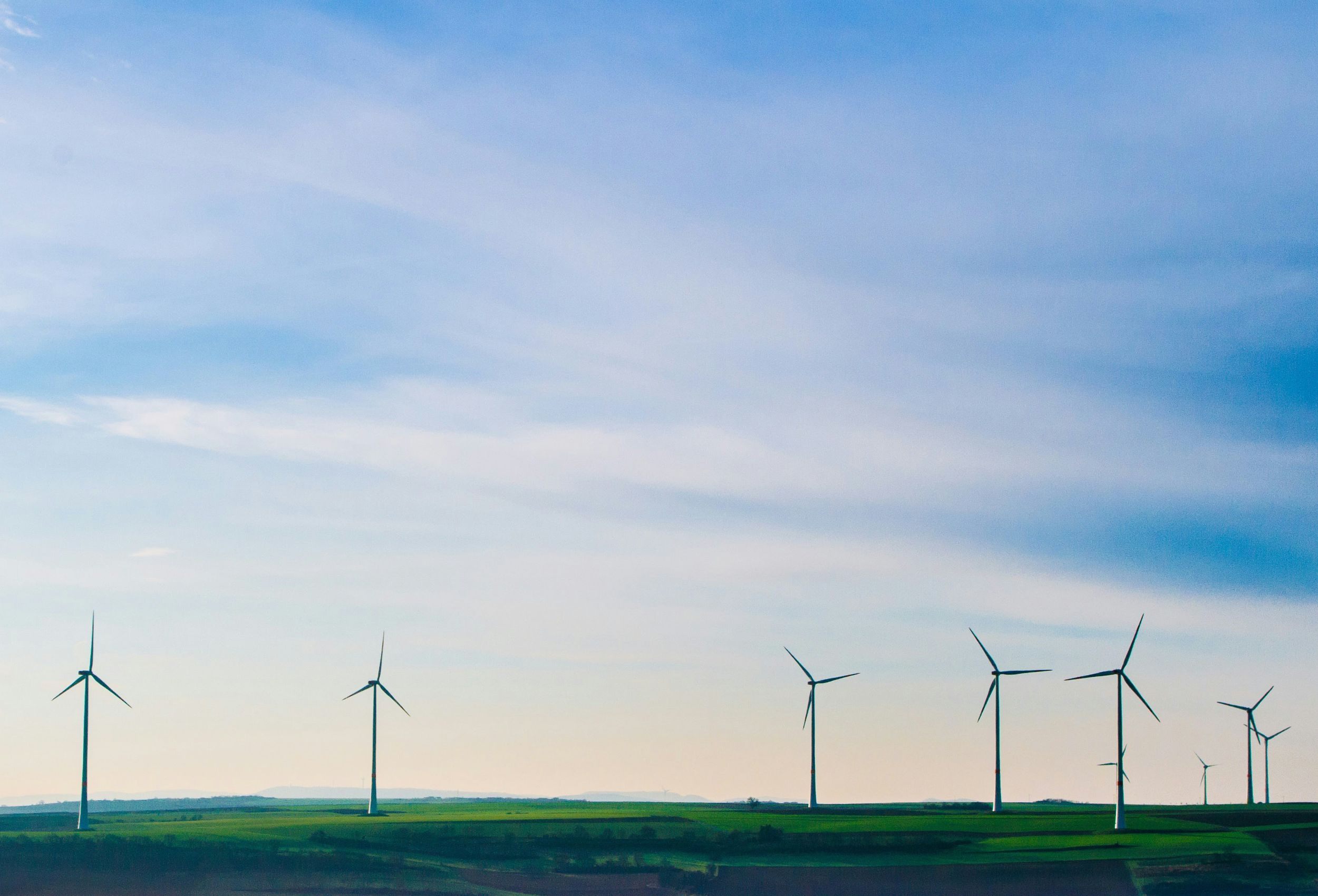 Wind turbines on a green field against blue sky