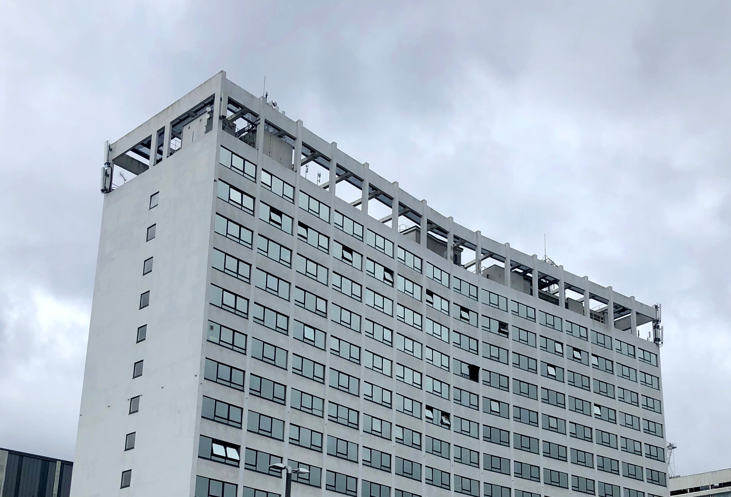 Large multi-storey white and glass building with rows of small windows