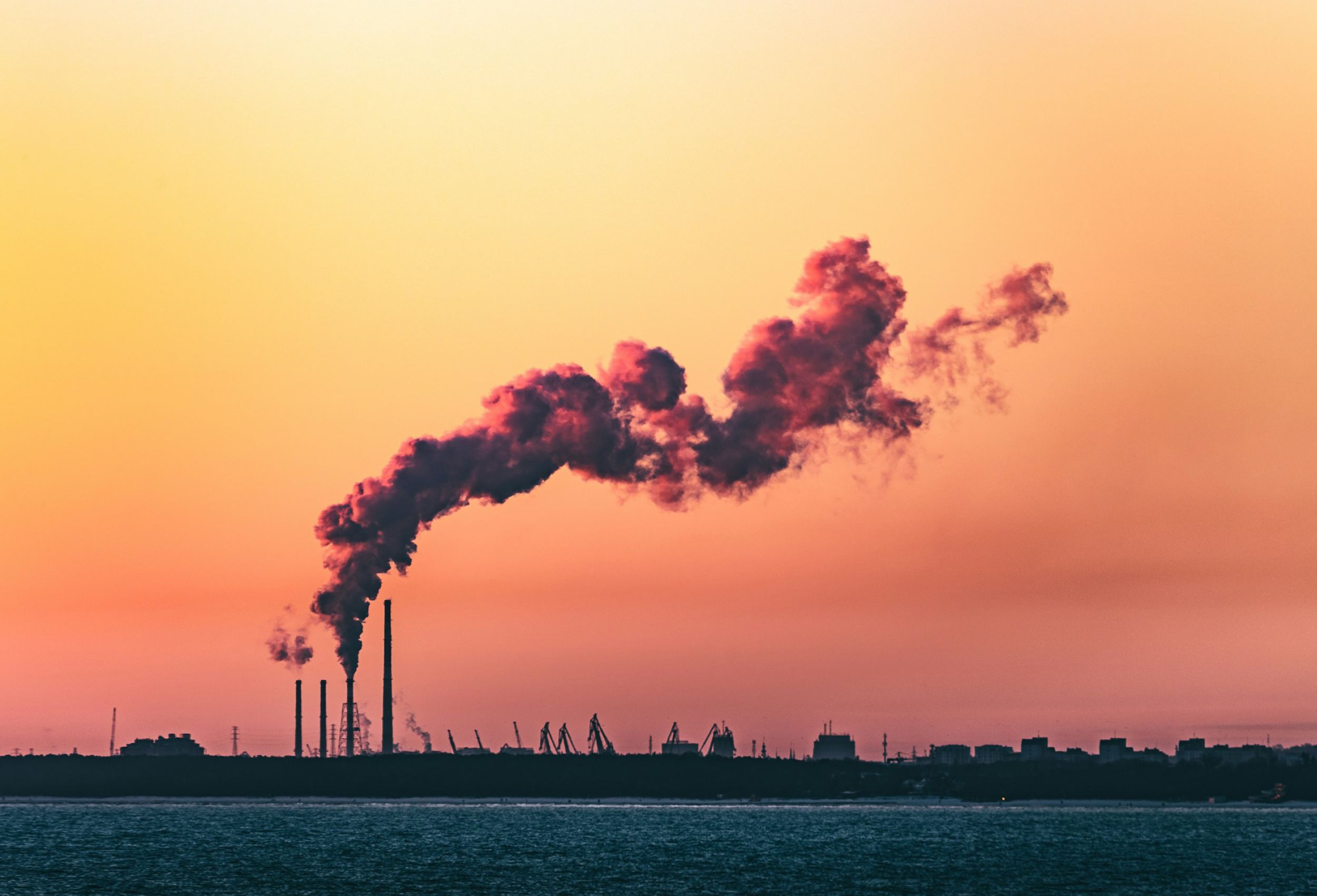 Smoking towers against orange sunset sky