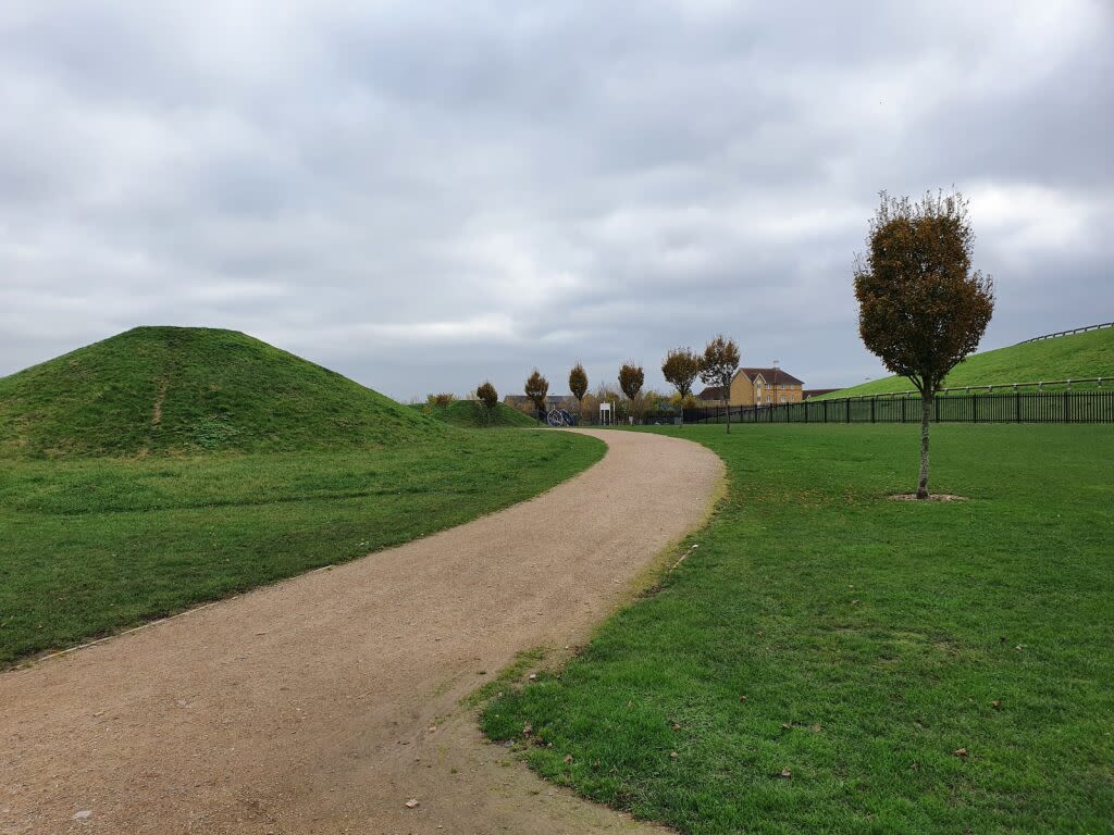 Thamesmead area with a man-made hill and a path winding through green open space.